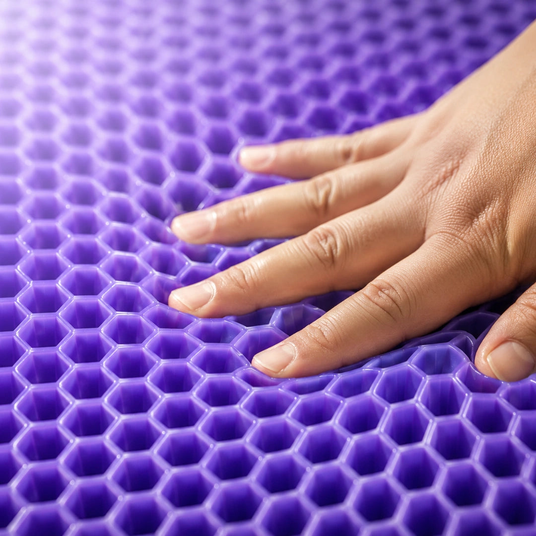 Une main appuie sur les alvéoles souples en gel violet du coussin Aevura